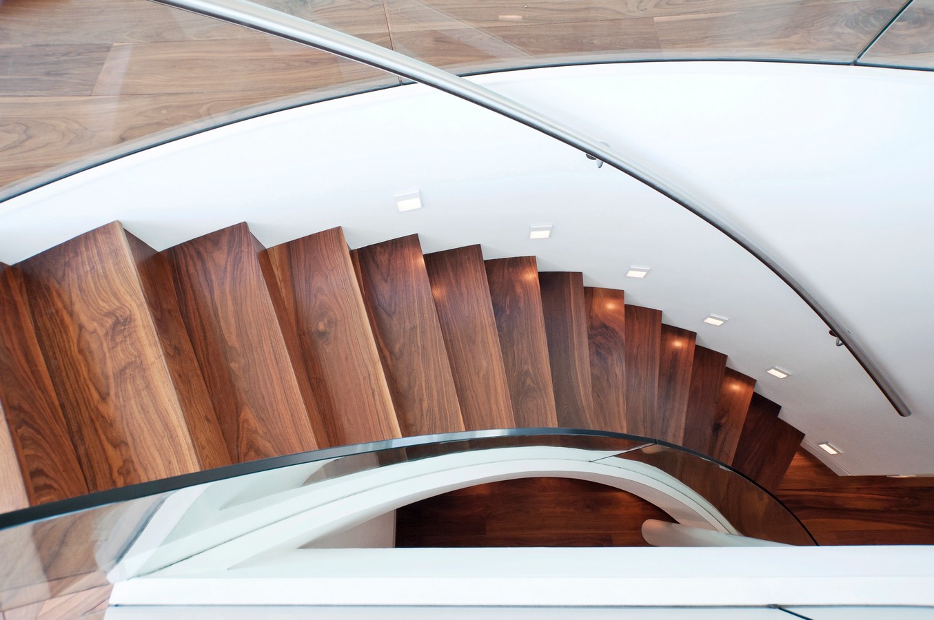 Curved walnut staircase with glass balustrade in Hamilton prestige home